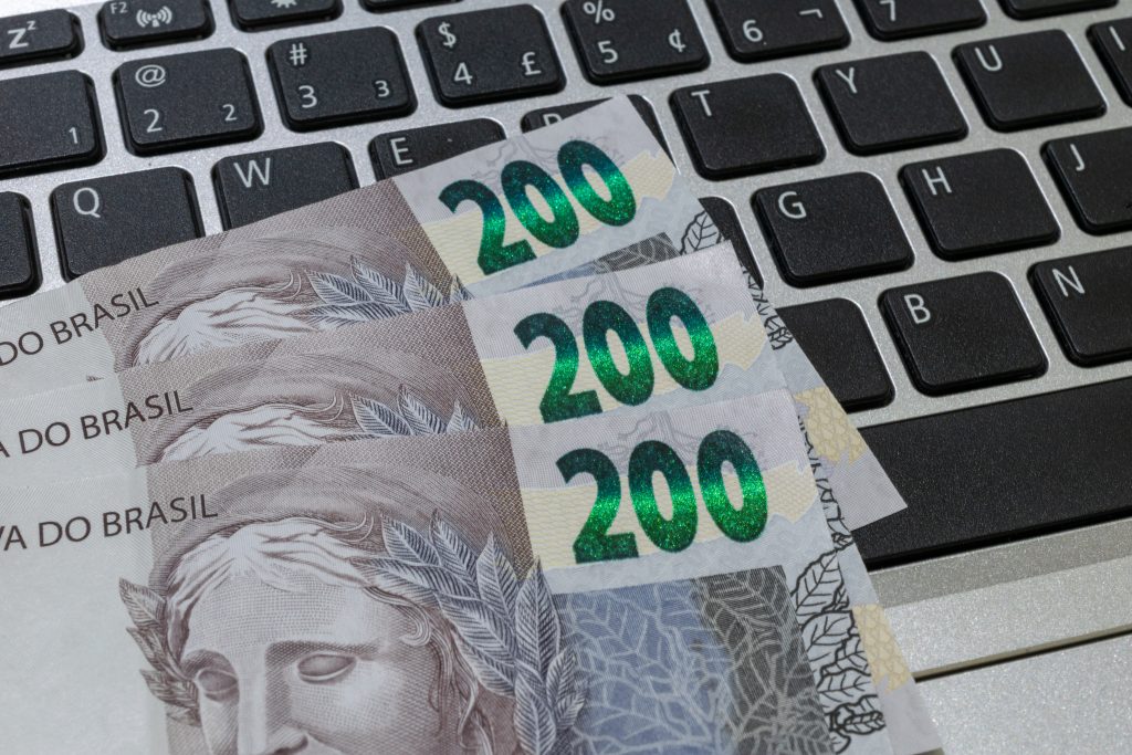 Notas de R$ 200 dispostas sobre um teclado de computador, representando dinheiro e finanças relacionadas a impostos, renda ou economia digital.